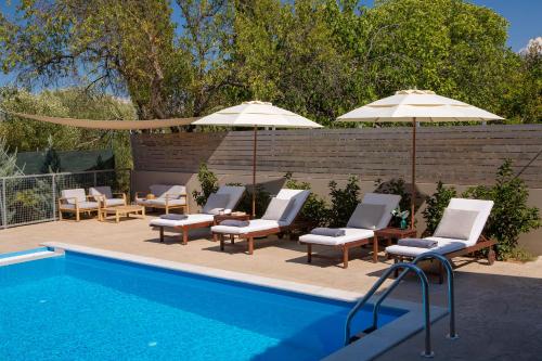 a swimming pool with chairs and umbrellas next to a swimming pool at Grappolo Lefkada Villas - Villa Vertzami just 2 km from Lefkada town in Apolpaina