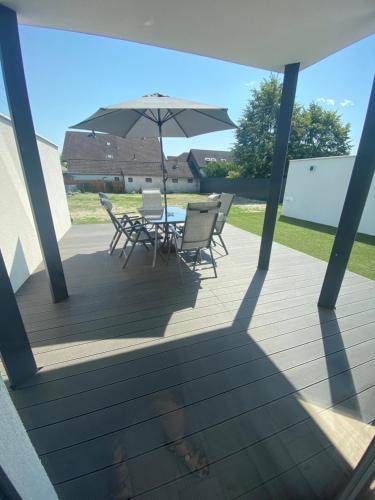 eine Terrasse mit einem Tisch, Stühlen und einem Sonnenschirm in der Unterkunft Bala-Home Apartmanok in Balatonboglár