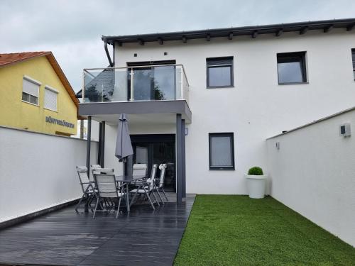 ein Haus mit einer Terrasse mit Stühlen und einem Tisch in der Unterkunft Bala-Home Apartmanok in Balatonboglár