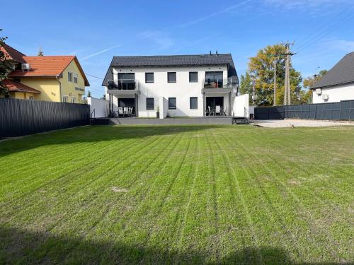 a large yard in front of a white house at Bala-Home Apartmanok in Balatonboglár