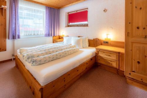 a bedroom with a large wooden bed with a window at Haus Suban in Längenfeld