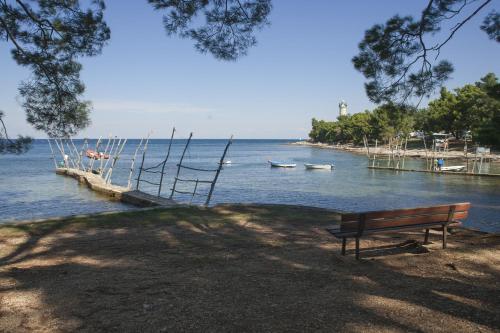 a bench sitting next to a body of water with boats at Villas Faro in Bašanija