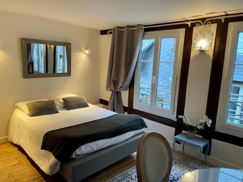 ein Schlafzimmer mit einem Bett und zwei Fenstern in der Unterkunft LA PARENTHÈSE DU CAPUCIN in Honfleur