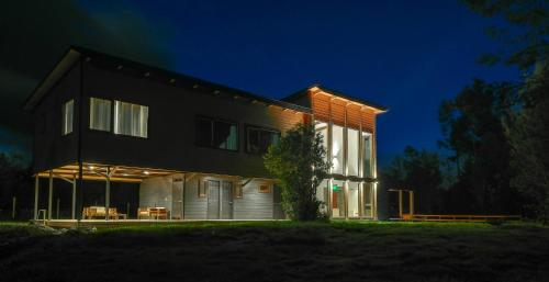 a black house with lights on it at night at Entre Volcanes Lodge in Ensenada