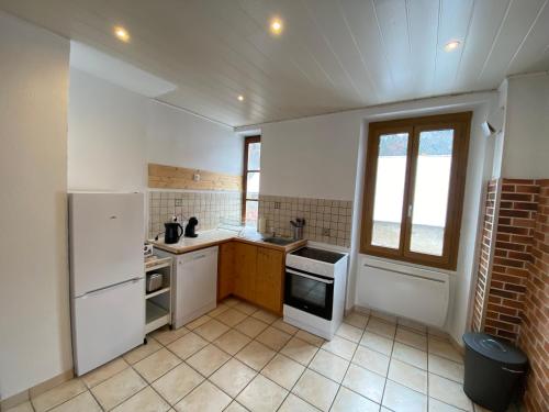 een keuken met witte apparatuur en een bakstenen muur bij Après l'école, appartement de charme in Oz