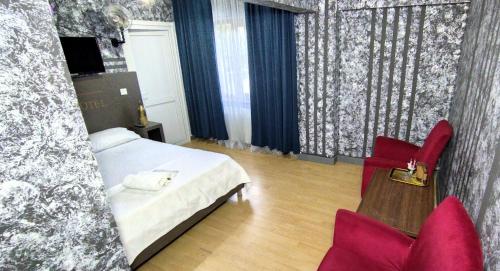 a bedroom with a bed and two red chairs at Zirkon Suit, Atasehir Otel, in Istanbul