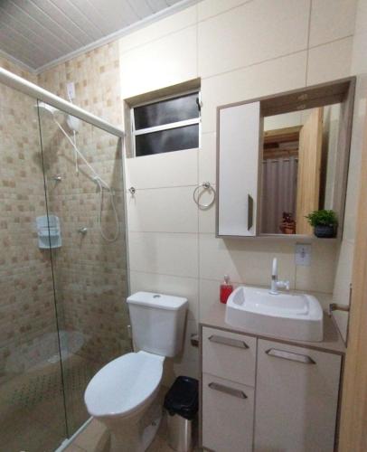 a bathroom with a toilet and a sink and a shower at SUÍTES PRAIA DO ROSA in Imbituba
