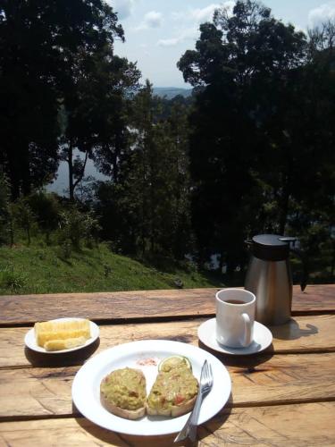 Una mesa con dos platos de comida y una taza de café. en Lake Nyamirima cottages, en Fort Portal