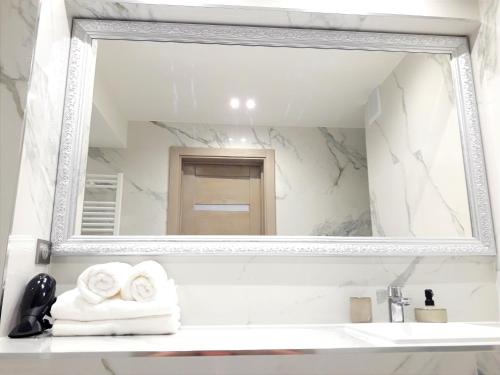 un espejo sobre un lavabo en el baño en LIGHT APARTMENT center city CHIȘINĂU, en Chişinău