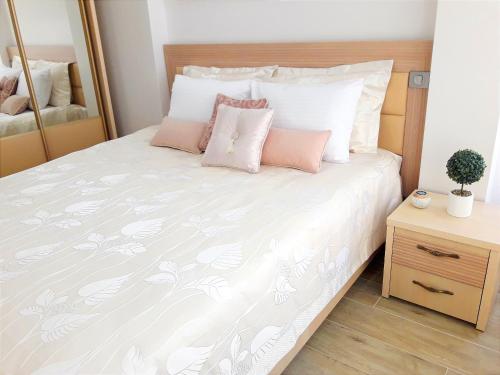 1 dormitorio con 1 cama con almohadas blancas y rosas en LIGHT APARTMENT center city CHIȘINĂU, en Chişinău