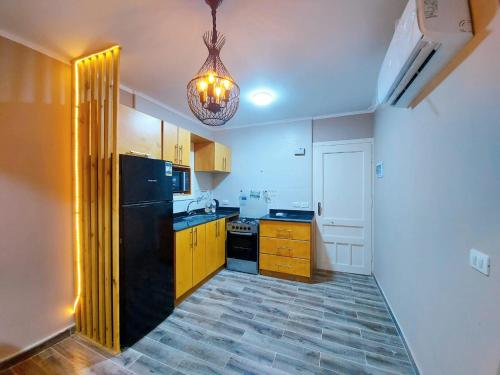 a kitchen with a black refrigerator and a chandelier at lovely one bedroom apartment within cozy compound including swimming pool, supermarket. perfect location at neama Bay with access to public transportation in Sharm El Sheikh