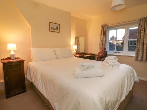 um quarto com uma cama branca e toalhas em Jenny's Cottage em Northallerton