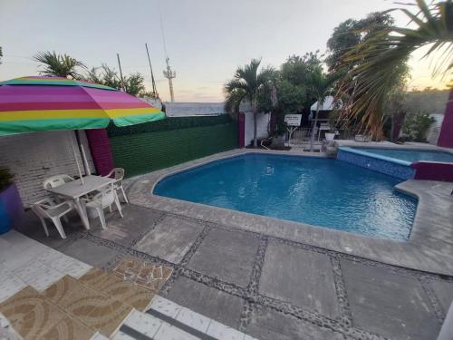a swimming pool with a table and an umbrella at Hotel Ayalamar Manzanillo in Manzanillo