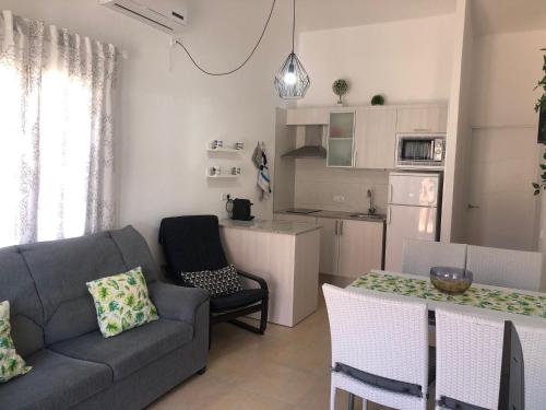 ein Wohnzimmer mit einem Sofa und einem Tisch sowie eine Küche in der Unterkunft Garbí & Xaloc apartamentos in Cala Galdana