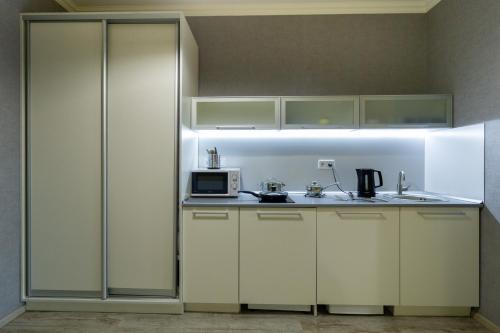 a kitchen with white cabinets and a microwave at Opera Passage Hotel & Apartments in Lviv