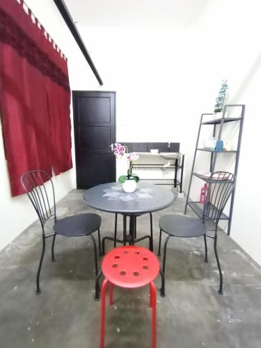 einen Tisch mit 2 Stühlen und einen Tisch mit einem roten Stuhl in der Unterkunft Minimalist Shop Stay @ Royal Town in Kuala Kangsar