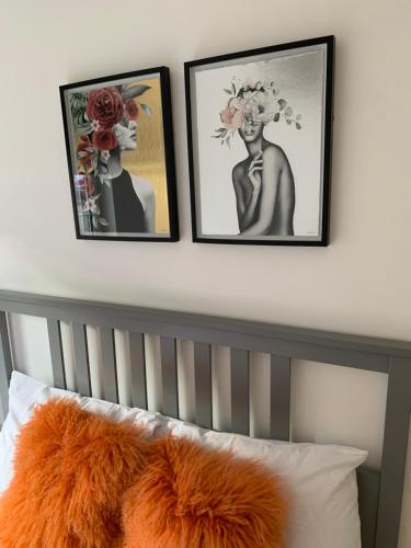 three framed pictures above a bed with an orange pillow at Causewayside in Edinburgh