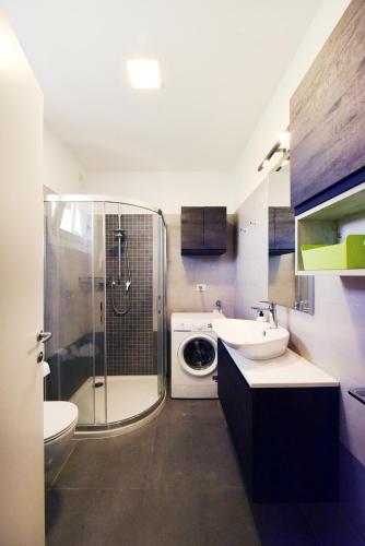 a bathroom with a shower sink and a washing machine at Residence Le Querce in Cordovado