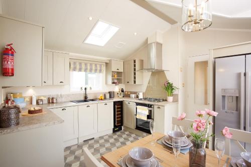 a kitchen with white cabinets and a table with pink flowers at JJs Lodge Azalea in York