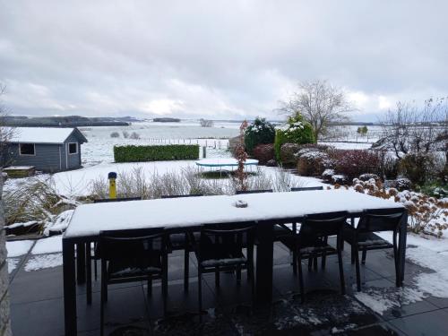 a table and chairs covered in snow in a yard at Bonheur à la campagne in Bastogne