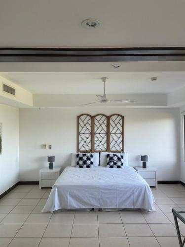 a white bedroom with a bed and two tables at Residence Nativa Las Vistas, appartement in Tarcoles