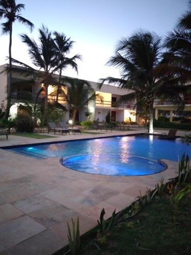 a swimming pool in front of a building with palm trees at Vila Saguaro in Trairi