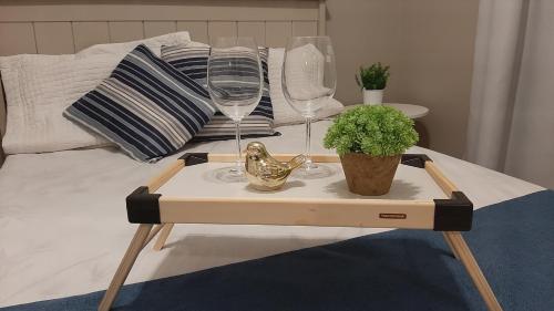 a tray with wine glasses and a plant on a bed at Mix aparts Tijucas -kit 10 in Tijucas