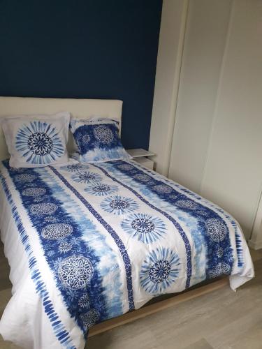 uma cama com um cobertor e almofadas azuis e brancas em l oiseau bleu em Cayeux-sur-Mer