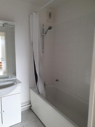 La salle de bains blanche est pourvue d'une douche et d'une baignoire. dans l'établissement l oiseau bleu, à Cayeux-sur-Mer