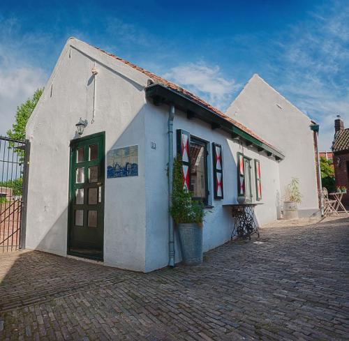 a small white building with a green door at Authentiek vakantiehuisje in Terneuzen