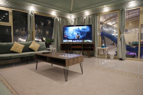 a living room with a tv and a table at Aljood Resort in Ras al Khaimah