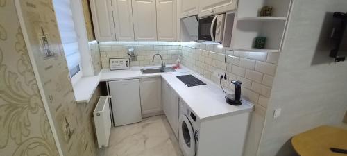 a small kitchen with white cabinets and a sink at Квартал Авиа in Vyshneve