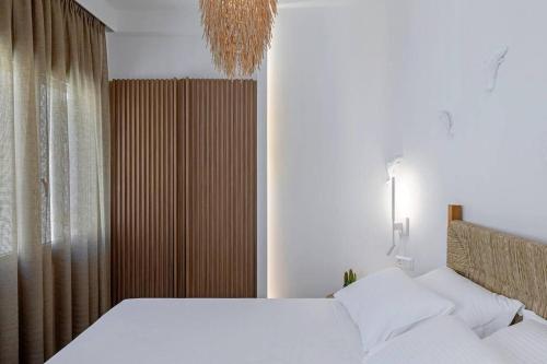 a bedroom with a large white bed and a chandelier at Boho Sapiens Marina - Romantic Cave in Adamas