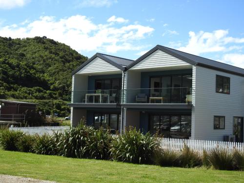 a white house with a hill in the background at Boathouse Apartments in Picton