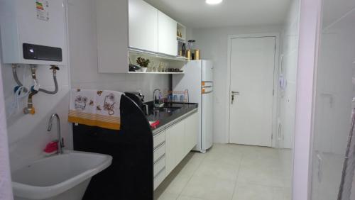 a white kitchen with a sink and a refrigerator at apartamento de frente para o mar com linda area de lazer in Arraial do Cabo