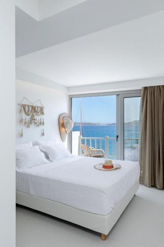 a white bedroom with a large bed and a window at Boho Sapiens Seagnature in Adamantas