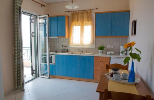 uma cozinha com armários azuis e uma mesa em Agnanti em Xi