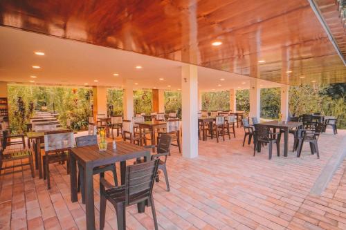 a patio with wooden tables and chairs and tables and tablesearcher at KANTU GARDEN LODGE in Moyobamba