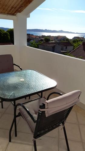 a glass table and a chair on a balcony at Apartments Mira in Bibinje
