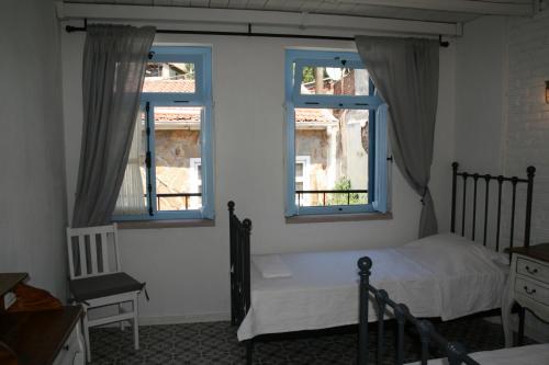 a bedroom with a bed and two windows at Cesmeli Han in Ayvalık