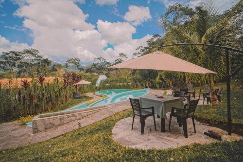 a table with chairs and an umbrella next to a pool at KANTU GARDEN LODGE in Moyobamba