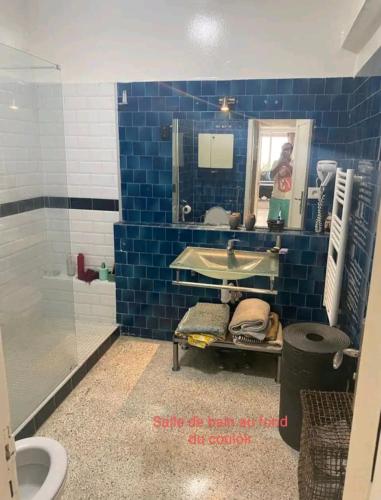 a blue tiled bathroom with a sink and a toilet at Appartement RIM in Casablanca