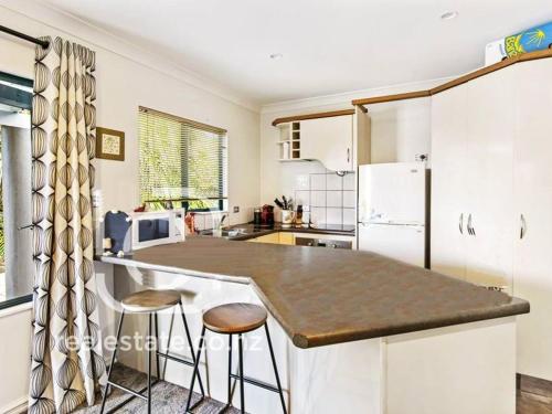 a kitchen with a large counter with two stools at Gulf Harbour Guest House Apartment in Auckland