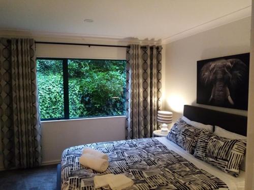 a bedroom with a bed and a large window at Gulf Harbour Guest House Apartment in Auckland