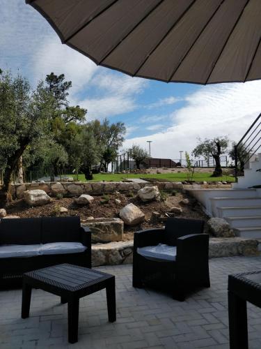 a patio with two chairs and a table and an umbrella at Poço e Meio - Padel & Pool in Santiago da Guarda
