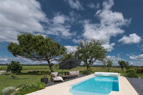 una piscina con 2 sillas y una sombrilla en Gîte - LA CLOCHETTE, en Lugon et l’Ile du Carney
