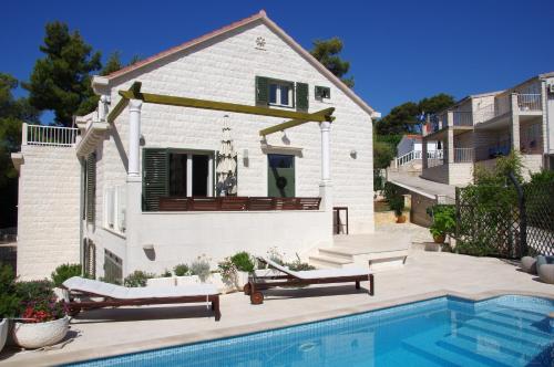 a house with a swimming pool in front of a house at Holiday Home Nevista in Sumartin
