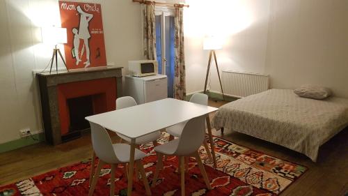 a room with a table and chairs and a bed at Grand studio et jolies chambres à louer in Passins