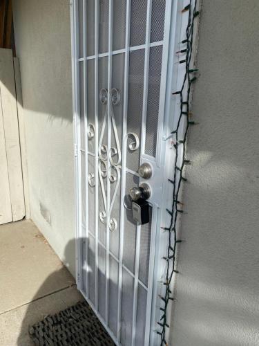 a white door with a metal gate with a chain at COMFY COZY ROOM ON QUIET CUL-DE-SAC in Los Angeles