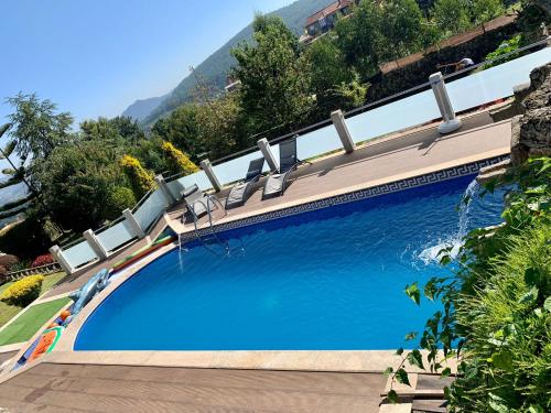 una gran piscina azul con sillas en un edificio en VILLA RAICES. Agradable casa con piscina, en Baiona